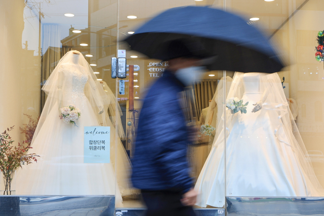 서울 마포구 아현동 웨딩거리 한 웨딩드레스 판매점 앞을 시민들이 지나가고 있다. 연합뉴스