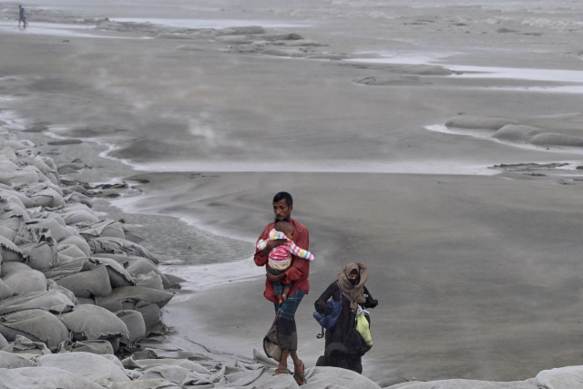 26일 인도양 북동부 벵골만에서 올해 첫 강력한 사이클론이 발생했다. 인도와 방글라데시 정부는 피해를 줄이기 위해 주민 100만명을 대피시켰다. 방글라데시 쿠아카타에서 사이클론 레말이 상륙한 후 한 남자가 어린이를 안고 피신하고 있다. AFP 연합뉴스