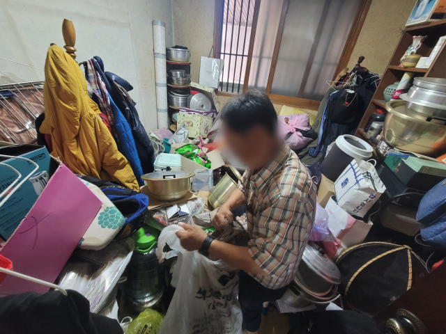 지난 14일 정용수(가명·69) 씨가 쓰레기로 뒤덮인 방을 혼자서 청소하고 있다. 박성현 기자