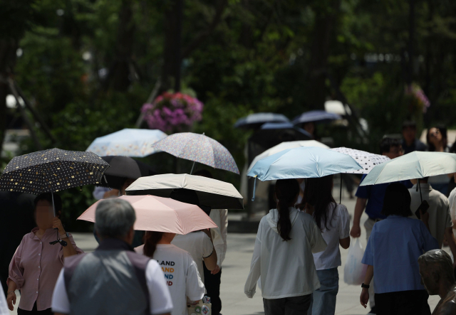 무더위가 이어진 지난 17일 서울 광화문광장에서 우산과 양산을 쓴 시민들이 걷고 있다. 연합뉴스