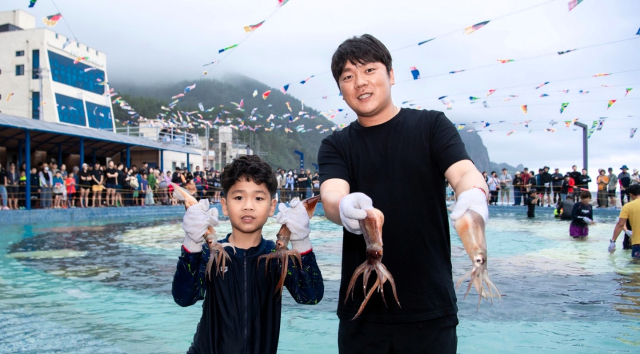 지난해 열린 울릉도 오징어축제. 오징어맨손잡기 프로그램에서 참가자가 오징어를 잡고 즐거워 하고 있다.울릉군 제공