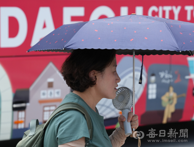 대구와 경북지역 곳곳에 폭염 경보가 발효된 지난 25일 대구 시내의 한 횡단보도에서 시민이 손풍기를 들고 양산을 쓴 채 길을 건너고 있다. 대구 기상청은 당분간 폭염이 지속될 것으로 보고 온열질환 등 더위로 인한 안전사고에 각별히 주의할 것을 당부했다. 매일신문 DB.