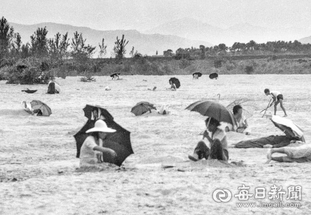 1977년 7월, 달성군 낙동강 화원유원지 백사장 곳곳에 자리를 잡은 시민들이 양산과 우산을 쓰고 모래찜질을 하고 있다. 사진=매일아카이빙센터