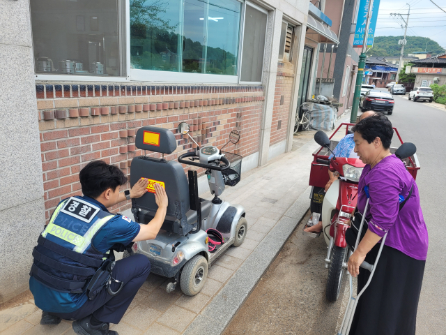 예천경찰서 호명지구대 소속 경찰관이 전동휠체어에 야광 반사지를 직접 부착하고 있다. 예천경찰서 제공