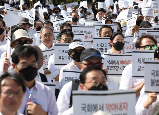 의대교수들이 3일 오후 서울 용산구 대통령실 인근에서 열린 한국의학교육평가원 무력화 저지 결의대회에서 손팻말을 들고 있다. 연합뉴스