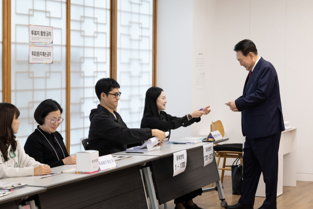 윤석열 대통령이 서울시교육감 보궐선거 투표 날인 16일 서울 용산구 용산공예관 투표소에서 선거사무원에게 신분증을 제시하며 본인 확인 절차를 거치고 있다. 연합뉴스