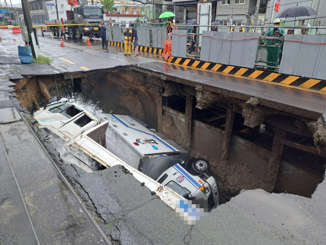 지난달 21일 오전 8시 45분께 부산 사상구 한 도로에서 가로 10ｍ, 세로 5ｍ, 깊이 8m가량의 대형 싱크홀이 발생해 트럭 2대가 빠져있다. 연합뉴스