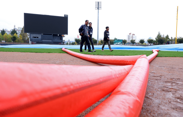 22일 전날 우천으로 중단됐다 재개를 앞둔 2024 신한 SOL뱅크 KBO 포스트시즌 한국시리즈 1차전과 2차전 경기가 예정된 광주 기아챔피언스필드에서 경기감독관들이 대형 송풍기를 이용한 건조작업이 진행 중인 경기장을 살펴보고 있다. 연합뉴스