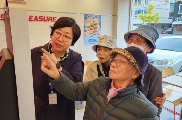 디지털 문해교육 어르신들이 안동 도심 한 매장에서 키오스크로 햄버거를 주문하는 체험 교육에 나서고 있다. 안동시는 전국 최초로 디지털 문해교육을 실시 연간 500여명의 어르신들이 각종 디지털 기기 사용법을 배우고 있다. 안동시 제공