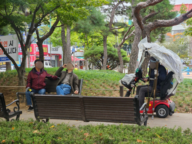 안심공원 벤치 옆에 전동스쿠터를 세워둔 채 친구들과 정답게 이야기를 나누는 중인 박 씨. 윤정훈 기자