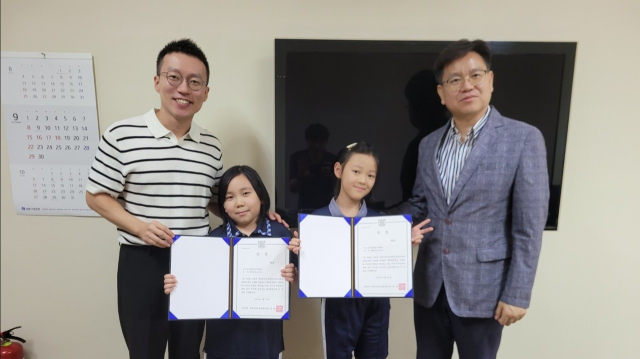 필리핀 마닐라에 있는 필리핀한국국제학교에 재학 중인 3학년 권솔희, 장아인 학생이 공모전에 참여해 대상을 받은 상금을 국내 소아암 어린이 환자를 위해 기부한 뒤 기념 촬영하고 있다. 필리핀한국국제학교 제공