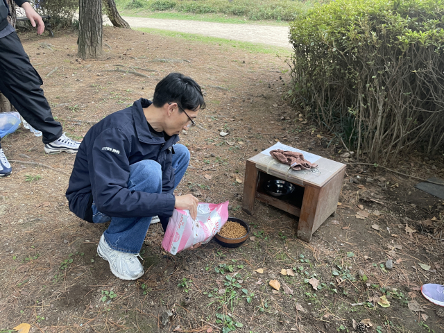 지난달 27일 냥플로깅을 주최한 동물권행동 카라의 한 활동가가 길고양이 급식소 안 사료 그릇에 사료를 채우고 있다. 한소연 기자