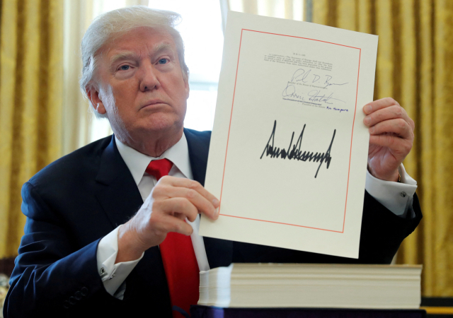 FILE PHOTO: Donald Trump displays his signature after signing the .5 trillion tax overhaul plan in the Oval Office of the White House in Washington, U.S., December 22, 2017. REUTERS/Jonathan Ernst/File Photo