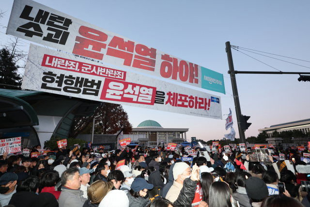 6일 오후 서울 영등포구 국회 앞에서 시민들이 대통령 탄핵을 촉구하는 손팻말을 들고 있다. 연합뉴스