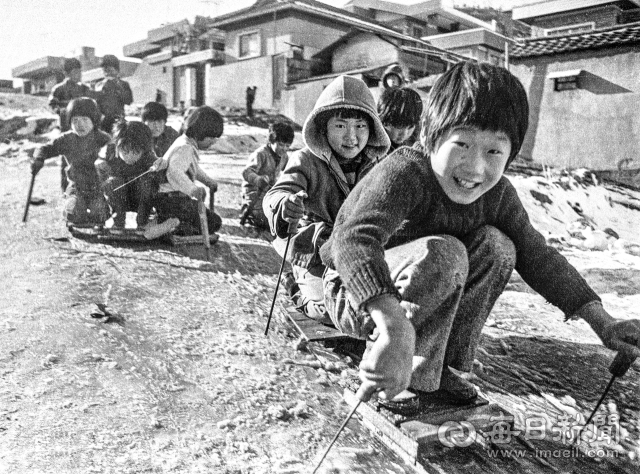 1970년대 대구 한 주택가 비탈길에 흘러내린 구정물이 빙판을 이루자 동네 아이들이 몰려 나와 썰매를 타고 있다. 사진=매일아카이빙센터