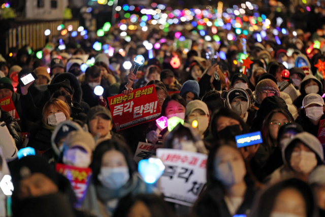 8일 오후 서울 여의도 국회 앞에서 열린 윤석열 탄핵 및 구속을 촉구하는 촛불문화제에서 참가자들이 관련 손팻말과 응원봉을 들고 있다. 연합뉴스