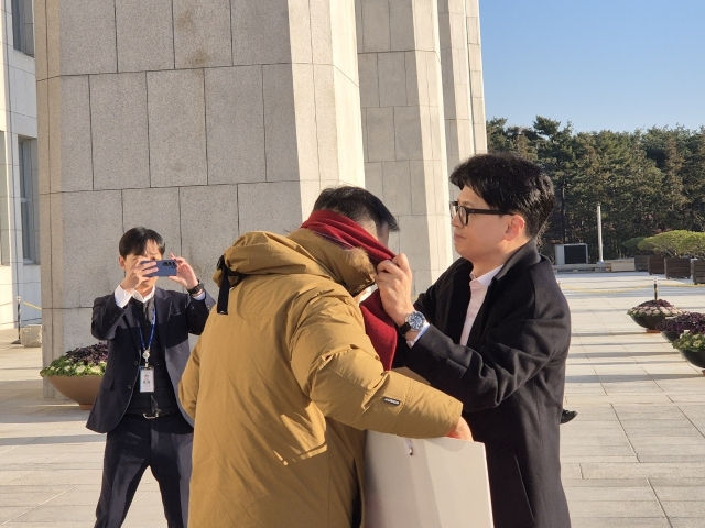 한동훈 국민의힘 대표가 14일 오전 국회 본청에 출근하던 중 탄핵 찬성 1인 시위 중인 김상욱 의원을 만나 자신의 목도리를 둘러주고 있다. 국민의힘 제공