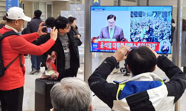 14일 오후 인천공항 2터미널에서 시민들이 윤석열 대통령에 대한 국회의 탄핵안 가결 중계 방송을 지켜보고 있다. 연합뉴스