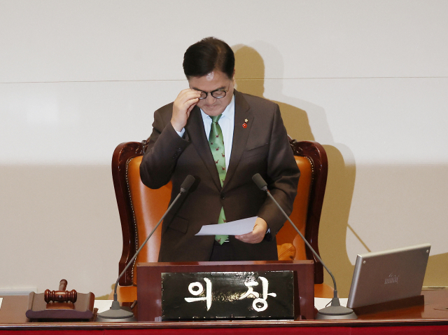 우원식 국회의장이 14일 오후 국회 본회의에서 윤석열 대통령 탄핵소추안 투표 결과를 전달받은 뒤 안경을 고쳐쓰고 있다. 연합뉴스