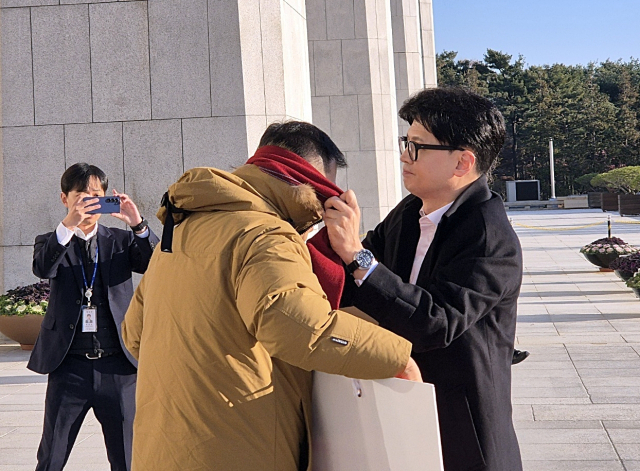 14일 오전 국민의힘 한동훈 대표가 국회 본청 앞에서 탄핵 찬성을 촉구하며 1인 시위를 하던 국민의힘 김상욱 의원에게 다가가 자기 목에 두르고 있던 빨간색 목도리를 풀어 김 의원에게 둘러주고 있다. 연합뉴스