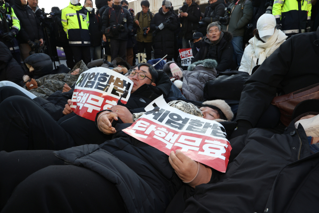 고위공직자범죄수사처가 내란 수괴(우두머리)·직권남용 혐의를 받는 윤석열 대통령의 체포영장을 유효기간인 6일 이전에 집행하겠다고 밝힌 가운데 2일 서울 용산구 한남동 대통령 관저 정문 앞 도로에 지지자들이 손팻말을 들고 누워있다. 연합뉴스