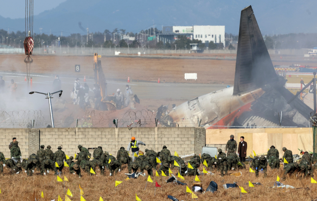 2일 오후 전남 무안군 무안국제공항 제주항공 참사 현장에서 합동조사단 관계자들이 로컬라이저 둔덕에 파묻힌 엔진을 꺼내는 작업 도중 기체 인근에서 용접하다가 불이나 연기가 피어오르고 있다. 연합뉴스