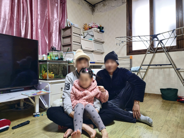 위암 말기인 박정호(50·가명, 오른쪽) 씨가 단전을 앞둔 곰팡이 가득한 집에서 배우자, 5살 딸과 함께 생활하는 모습. 김지효 기자