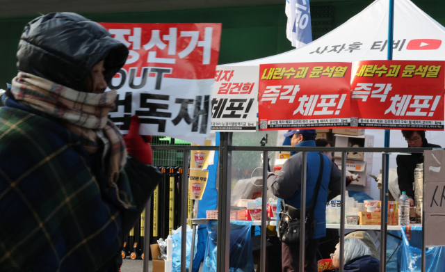 13일 오전 서울 용산구 한남동 대통령 관저 부근에서 한 탄핵 반대 집회 참가자가 탄핵 찬성 집회 현장을 지나가고 있다. 연합뉴스