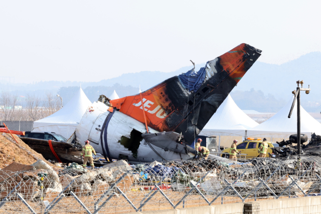 제주항공 여객기 참사 16일째인 13일 오전 무안국제공항 사고 현장에서 소방 대원들이 기체에 덮인 방수포를 걷어내고 있다. 연합뉴스