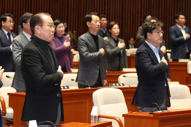 국민의힘 권영세 비상대책위원장과 권성동 원내대표를 비롯한 의원들이 15일 서울 여의도 국회에서 열린 비상 의원총회에서 국기에 경례하고 있다. 연합뉴스