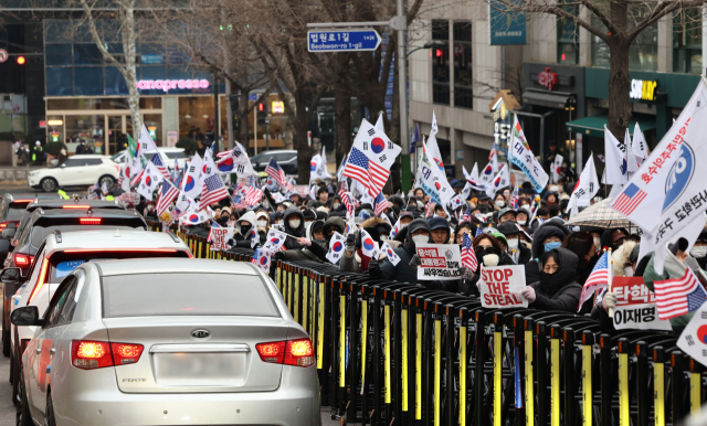 윤석열 대통령이 체포적부심사에 불출석한 16일 오후 서울 서초구 중앙지방법원 앞에서 윤 대통령 지지자들이 태극기를 흔들고 있다. 연합뉴스