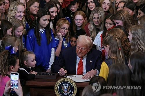 다양한 나이대의 여성 선수들에게 둘러싸여, 성전환자 여성 스포츠 출전금지 행정명령에 서명하는 트럼프 대통령. 연합뉴스