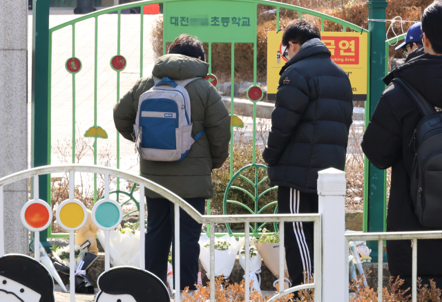 11일 오전, 초등생 1학년 여아가 살해당한 대전 서구 한 초등학교 앞에서 학생들이 시민이 두고 간 편지와 꽃, 과자, 인형 등을 바라보고 있다. 연합뉴스