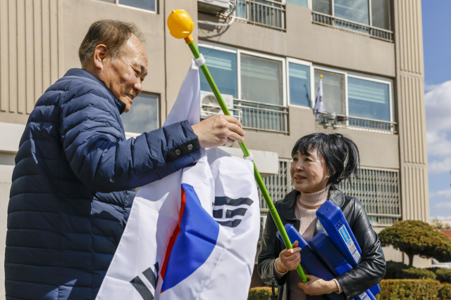 칠곡군 왜관읍 무성아파트 김금숙 이장(오른쪽)이 주민에게 태극기를 건네며 3·1절 태극기 달기 운동의 의미를 설명하고 있다. 칠곡군 제공