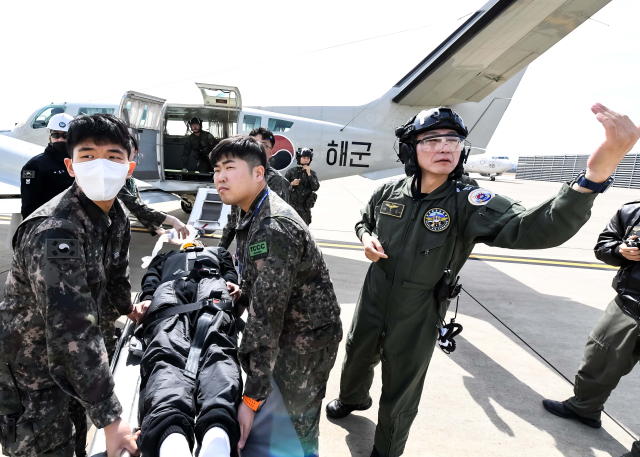 12일 포항 동방 해상에서 자유의 방패(Freedom Shield) 연습의 일환으로 진행된 전시 해상 전상자 탐색구조 및 합동의무지원 훈련에서 이국종 국군대전병원장(오른쪽)을 비롯한 구조·의무대원들이 중상자를 후송하기 위해 인원 이송이 가능한 해군 항공기(CARV-II)로 이동하고 있다. 해군항공사령부 제공.