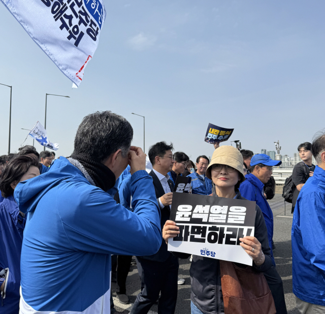 더불어민주당 의원, 당직자, 보좌진 등이 15일 국회에서 광화문으로 거리 행진을 하는 도중 임미애 의원이 피켓을 들고 있다.