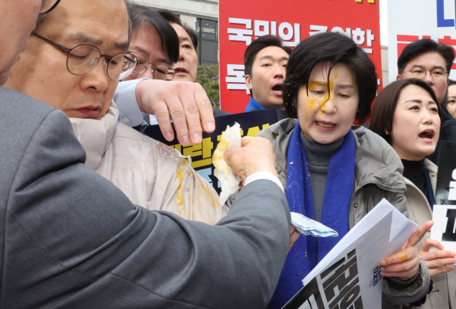 백혜련 더불어민주당 의원이 20일 서울 종로구 헌법재판소 앞에서 열린 민주당 원내부대표단의 윤석열 대통령 신속 파면 촉구 기자회견 도중 얼굴에 계란을 맞아 닦아내고 있다. 연합뉴스