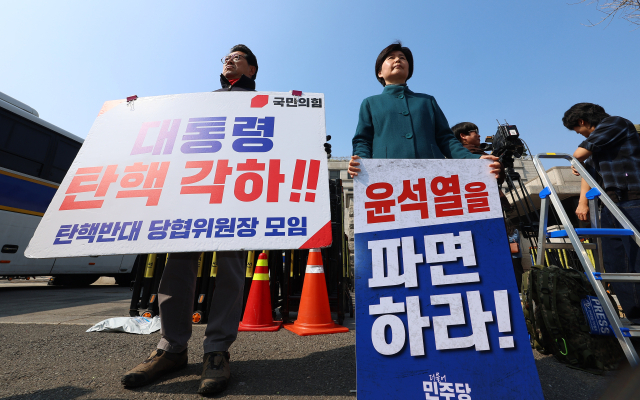 21일 서울 종로구 헌법재판소 앞에서 더불어민주당 백혜련 의원(오른쪽)과 국민의힘 수원시을 홍윤오 당협위원장이 각각 윤석열 대통령 파면 촉구 및 탄핵 반대 1인 시위를 하고 있다. 연합뉴스