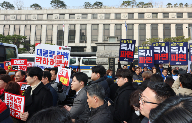 21일 서울 종로구 헌법재판소 앞에서 국민의힘 의원들(왼쪽)과 민주당 의원들(오른쪽 뒤)이 각각 탄핵 반대와 촉구 기자회견을 하고 있다. 연합뉴스